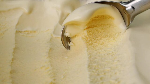 Slow motion Hands scoop Vanilla ice cream out of container with spoon.