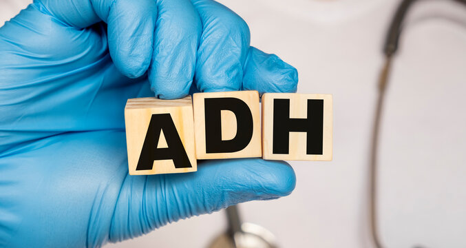 ADH Antidiuretic hormone vasopressin - word from wooden blocks with letters holding by a doctor's hands in medical protective gloves. Medical concept.