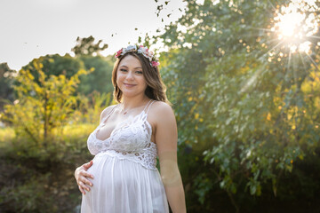 Beautiful portrait of a pregnant young woman in a field one hand on maternity stomach dead space to add content 