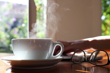 Woman working at home with laptop and hot drink with glasses on desk