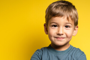 Portrait of happy joyful small caucasian boy in front of yellow background looking to the camera - Childhood growing up and concept - front view waist up copy space - obrazy, fototapety, plakaty
