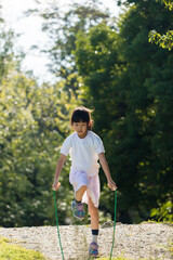 夏の公園で縄跳びを遊んでいる可愛い子供