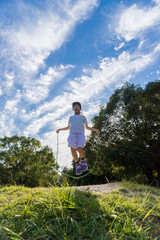 夏の公園で縄跳びを遊んでいる可愛い子供