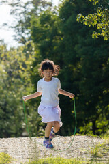 夏の公園で縄跳びを遊んでいる可愛い子供