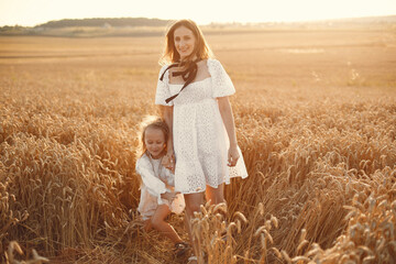 Family in a wheat field. Woman in a white dress. Girl with straw hat.