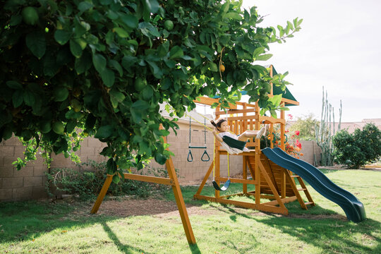 Child on swing set in suburban backyard