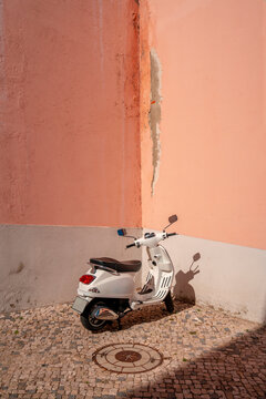 Moped parked agains pink wall