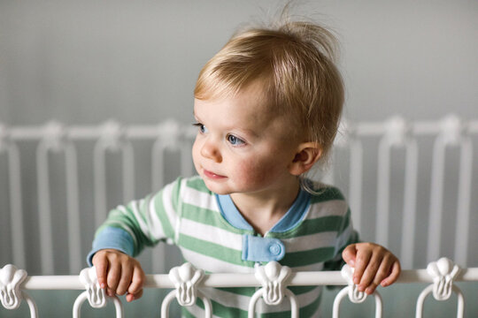 portrait of a toddler standing in his crib