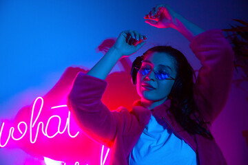 Woman with headphones dancing in neon lights