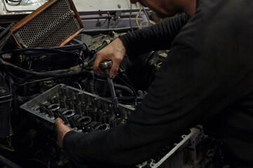 Crop man fixing broken car in workshop