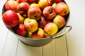 Ripe red apples and watermelon in washtub on white wooden background top view