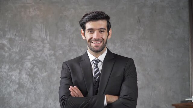 B roll of Successful businessman wearing suit crossing arms smiling to camera. Young company leader dreaming of a business success. Confident male ceo executive manager looking and smile with camera.