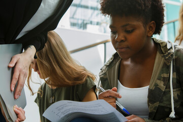 Calm pensive student checking exam result in papers while sitting in auditorium after class in university