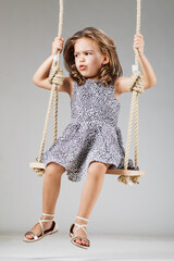 happy little girl swinging on a wooden swing