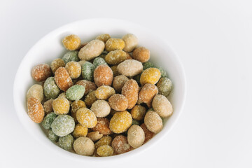 Salted peanuts covered with glaze in a ceramic bowl on a white background. Delicious appetizer. Space for text.