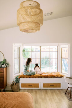 Mom and daughter sitting in bay window in home