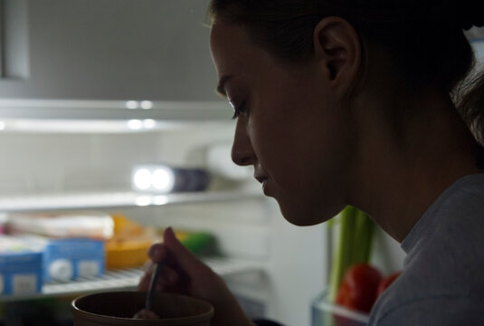 Hungry woman eating dessert at night