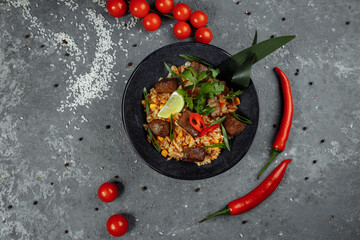 Fried rice with beef and vegetables on a gray textured background