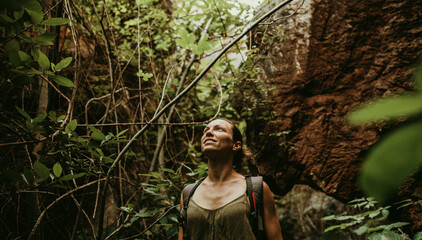 Woman trekking in forest between rock and trees