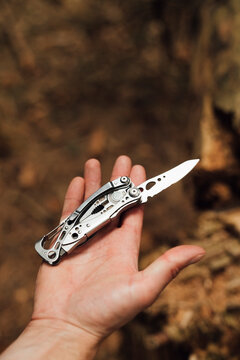 Close-up of male hiker's hand with penknife in forest