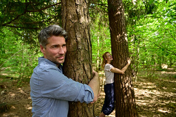 Man and woman hugging tree while standing in forest