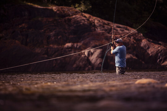 Fly fisherman casting with two handed rod in river