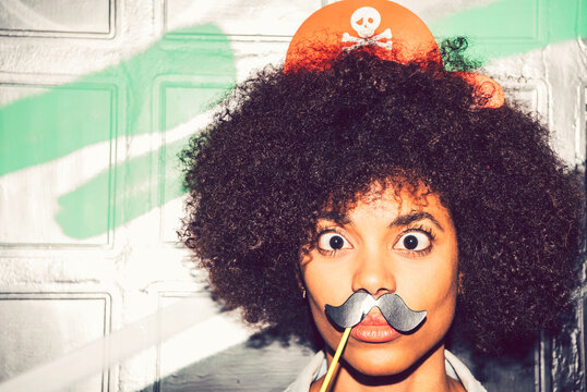 Close-up of woman with fake mustache making face against wall at night