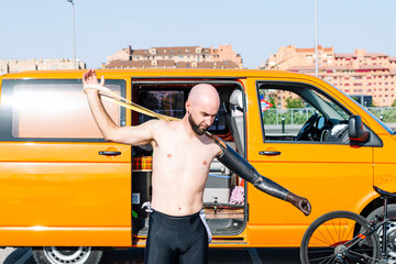 Bald adaptive athlete wearing artificial hand while standing against van
