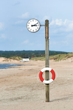 Inflatable tube on clock pole at beach against sky