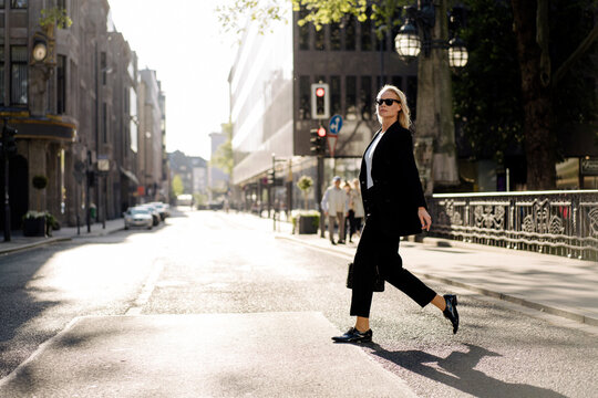 Fashionable businesswoman crossing street in city