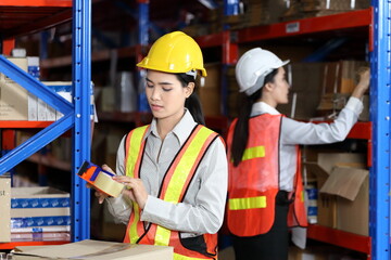 Asian workers are packing product in cardboard box while working in warehouse with full safety equipment for distribution and storage business