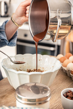 Woman hand pouring melted chocolate in bowl at kitchen