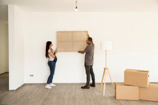 Couple carrying window frame while moving in new house