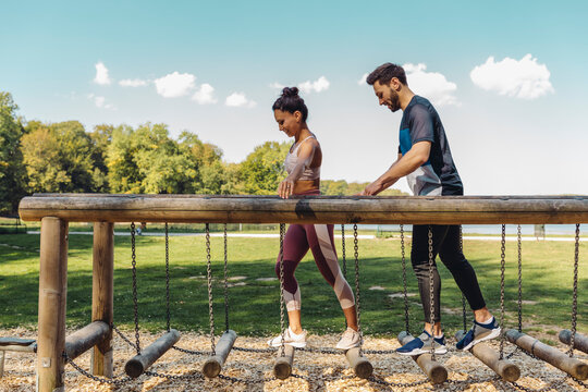 Man and woman walking on balance logs on a fitness trail