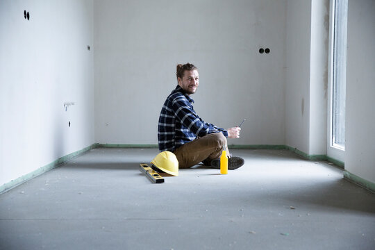 Construction worker sitting on floor in empty house at construction site