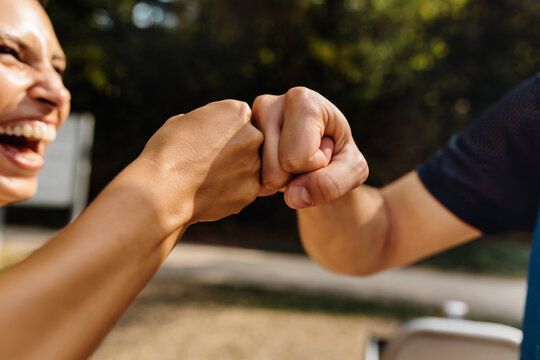 Man and laughing woman fist bumping on a fitness trail