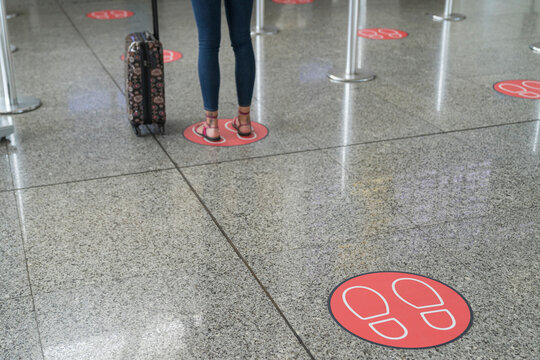 Legs of woman standing on markings for social distancing at airport