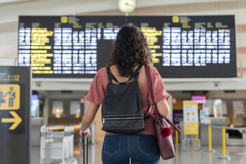 Young woman checking her flight in time board at airport