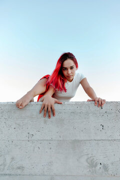 Young woman climbing wall against clear sky