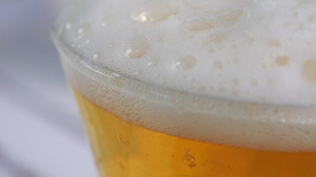 Top of beer glass in closeup displaying all the tiny bubbles and bright white foam. Beer and other beverages concept video.