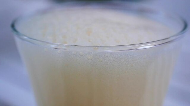 Top of beer glass in close up as more beer is added showing the white foam increasing in slow motion. Beer and other beverages concept video.