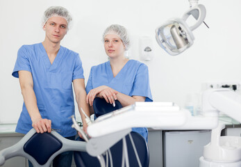 Obraz premium Two professional confident dentists posing near dental chair in clinic. High quality photo