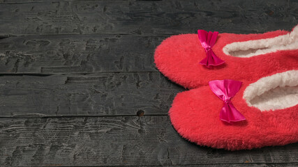Red fur Slippers on a black wooden background.