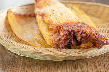 closeup of chicken tamale with red sauce