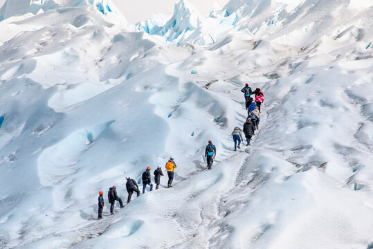 grupo de personas en fila subiendo por el hielo hacia la sima del glaciar Perito Moreno, en la patagonia Argentina
