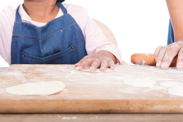 A little Chinese girl in a blue apron is learning to make dumplings