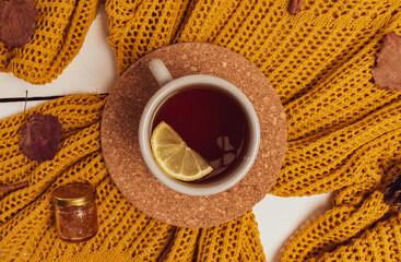 Cozy flat lay of lemon tea cup, yellow sweater, leaves, cinnamon sticks and pine cones. Autumn composition.