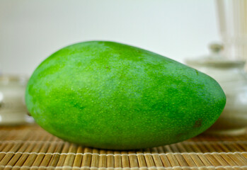 A green mango on bamboo mat surface close up fruit