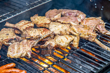 Tomahawk rib beef steak ans sausages on hot black grill with flames bbq