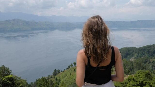 Ultra slow motion shot of young caucasian woman enjoying view of Lake Toba from Samosir Island in North Sumatra, Indonesia
